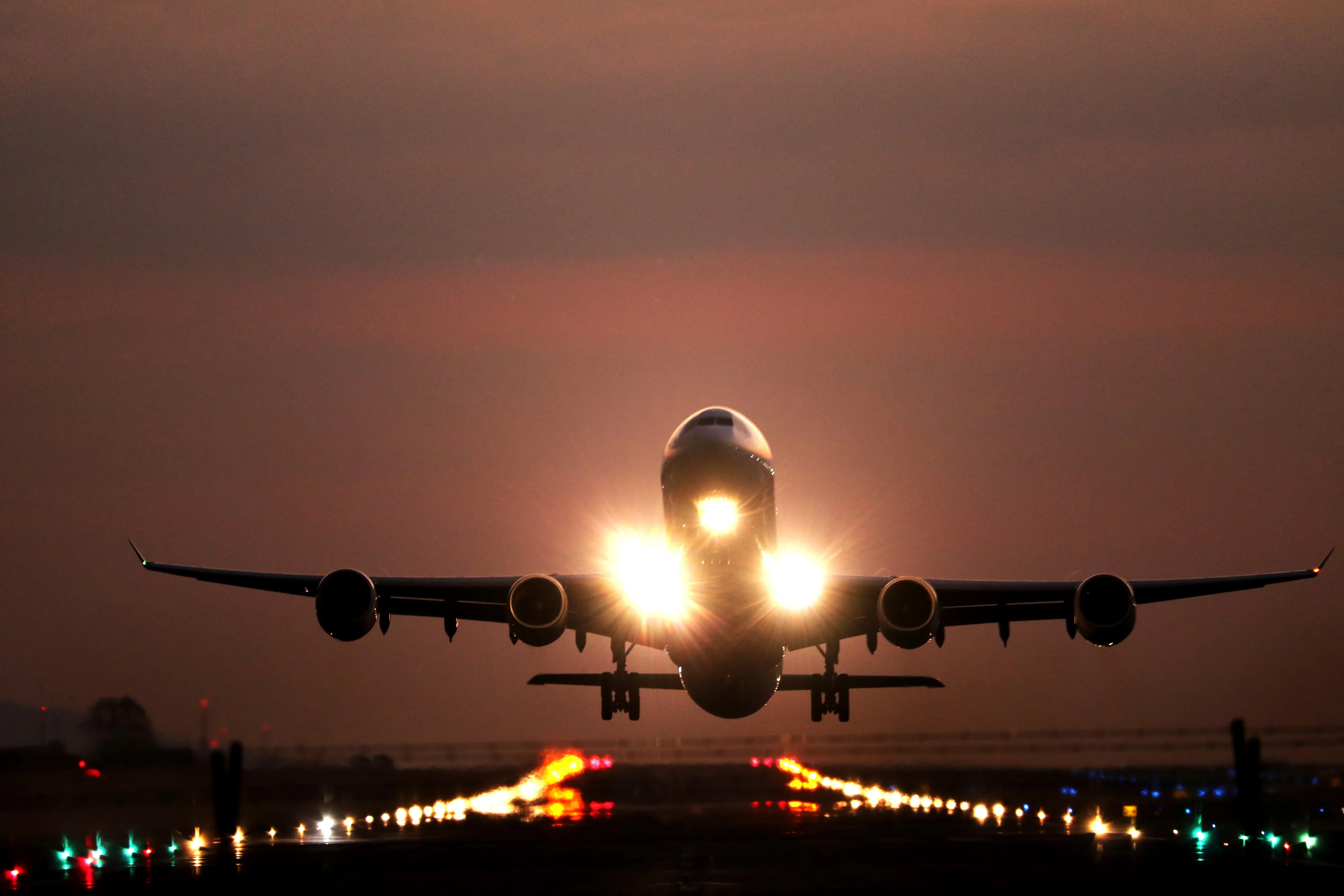 Aircraft taking off from a lit runway at dusk